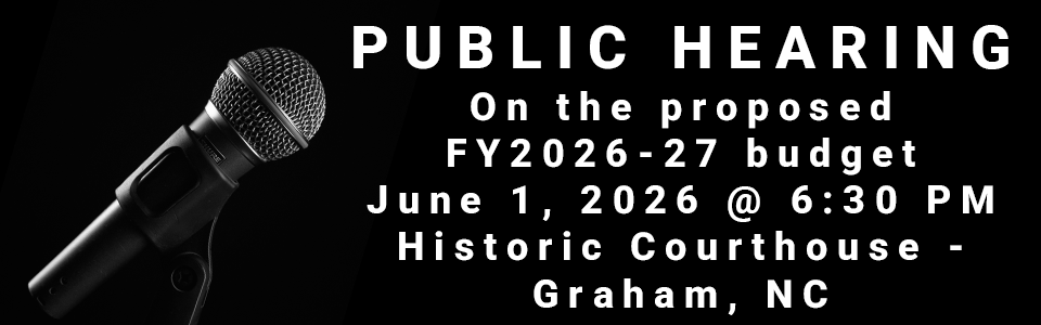 Image of microphone, announcing a public hearing on the FY2026-27 budget on June 1 2026, 6:30PM, at the Historic Courthouse in Graham, NC